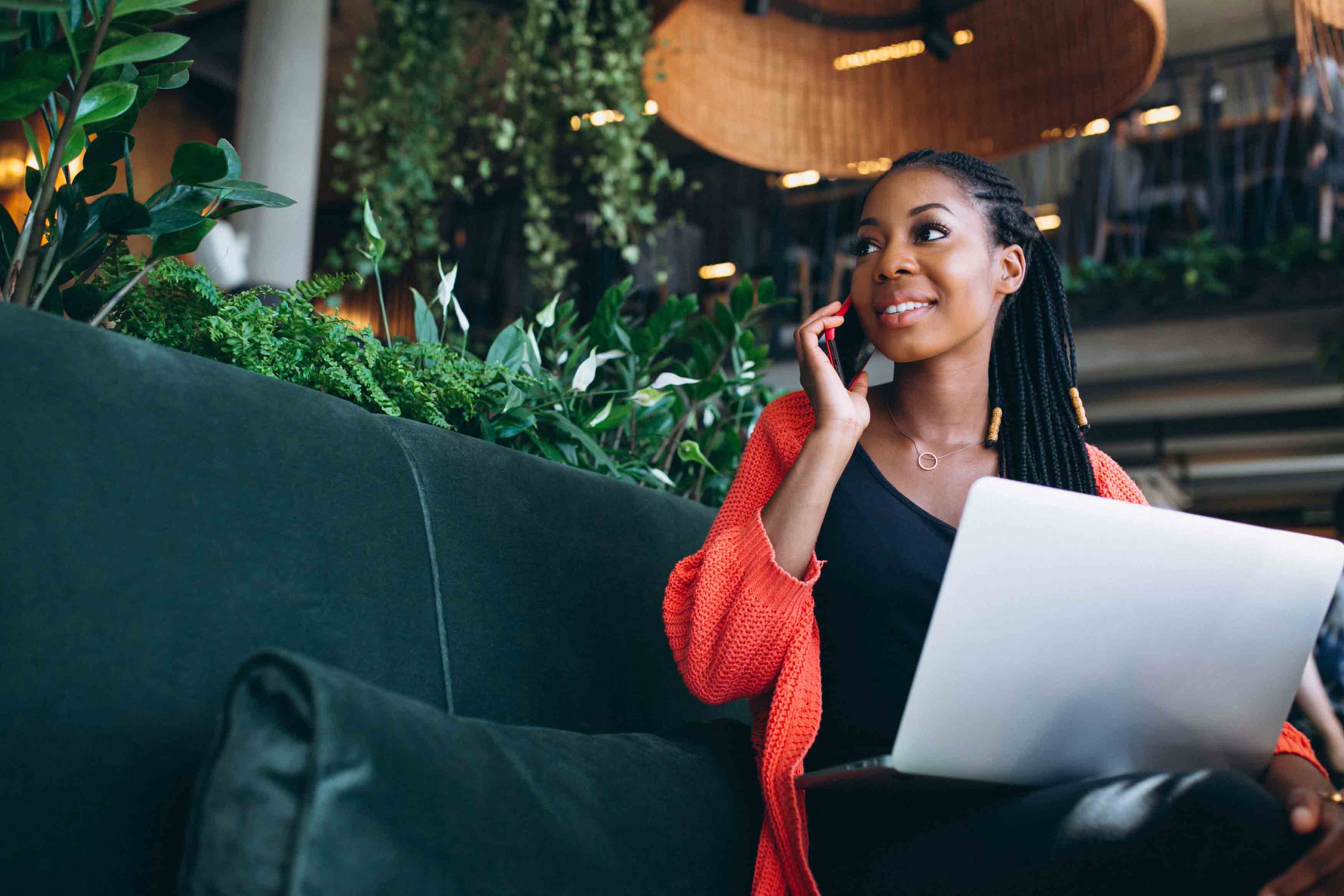 Woman entrepreneur using phone while working on laptop